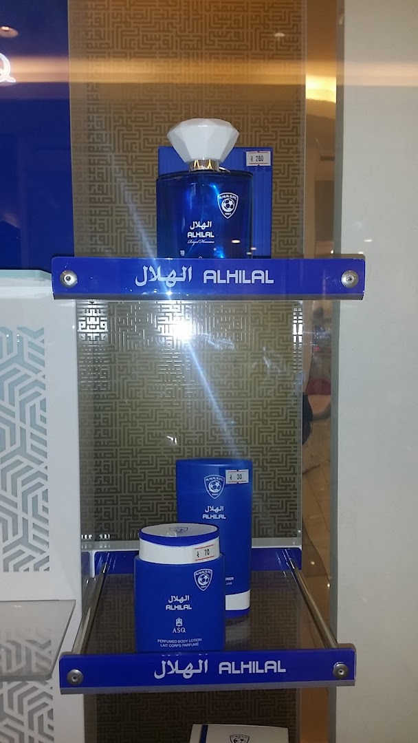Display of Al Hilal branded perfume and body lotion products in blue packaging.