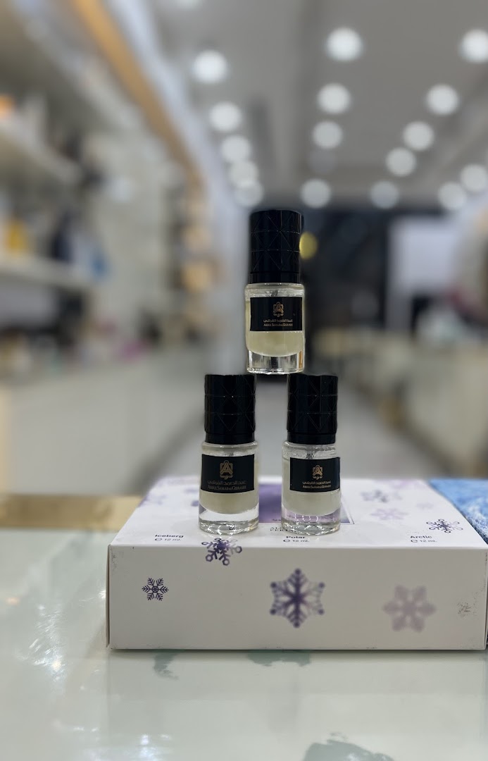 Three small perfume bottles are stacked on a box with snowflake designs.