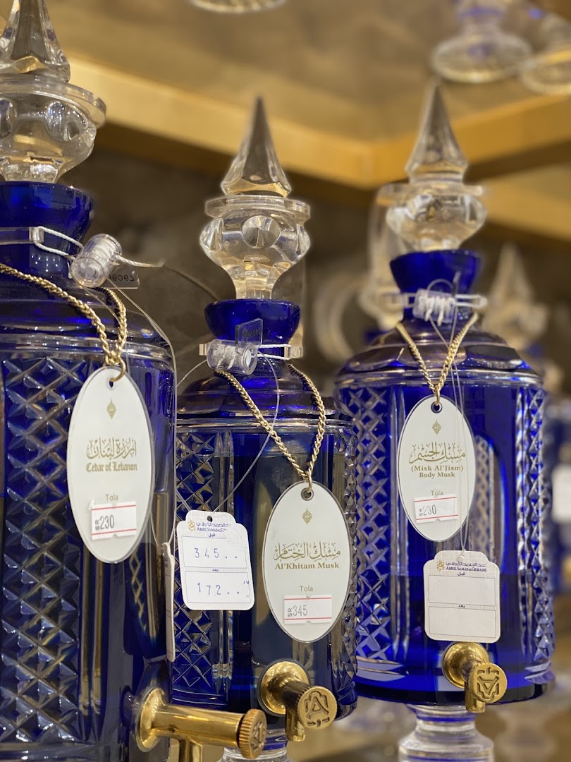 Close-up of ornate blue glass perfume bottles with decorative stoppers and price tags.
