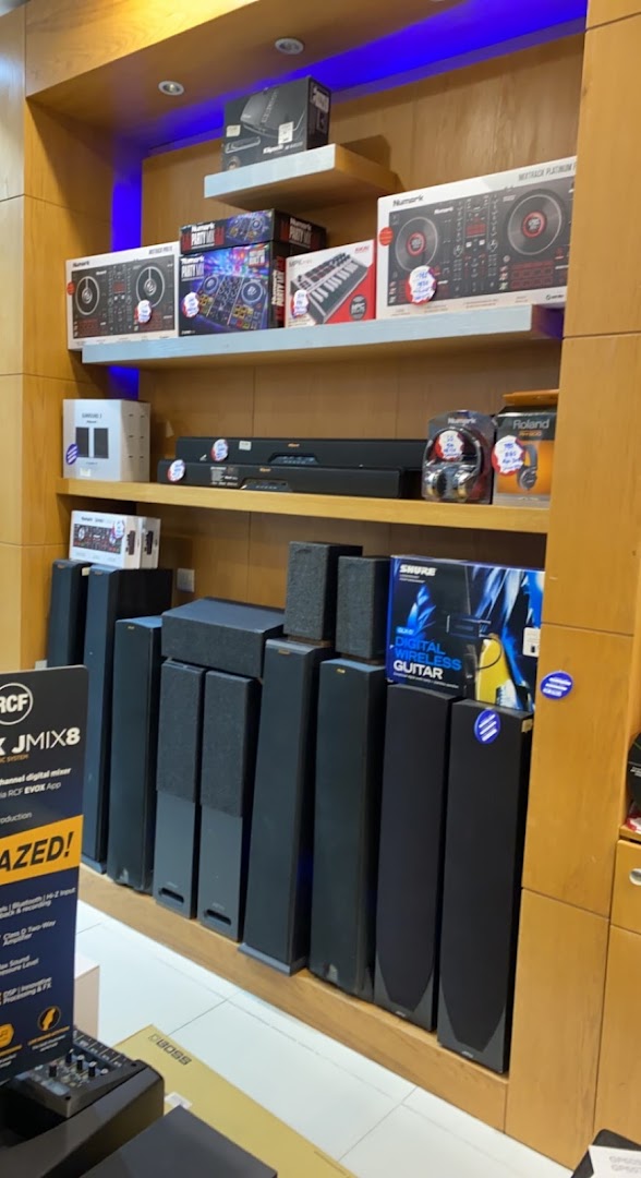 A display of audio equipment including DJ controllers, speakers, headphones, and mixers.