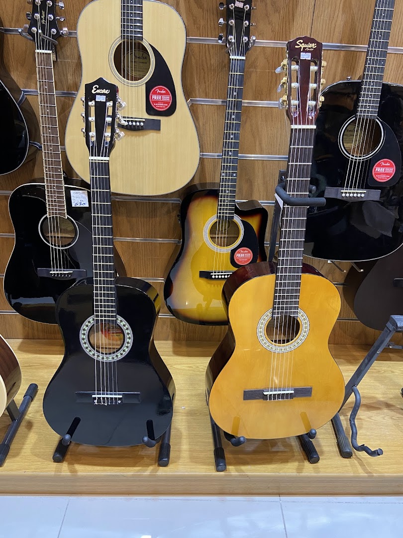 A display of various acoustic guitars, including black, natural wood, and sunburst finishes.