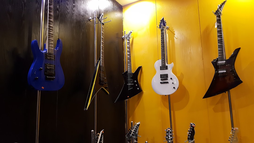 A display of electric guitars in various colors and styles, mounted on stands.