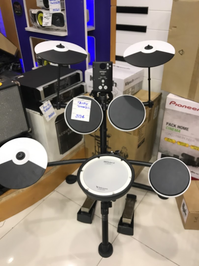A digital drum kit with cymbals and pedals is displayed in a retail store.