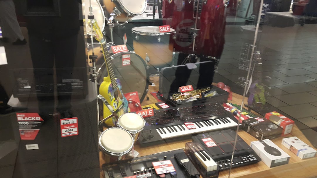 A shop window display featuring musical instruments and electronics, with several items marked 'SALE'.
