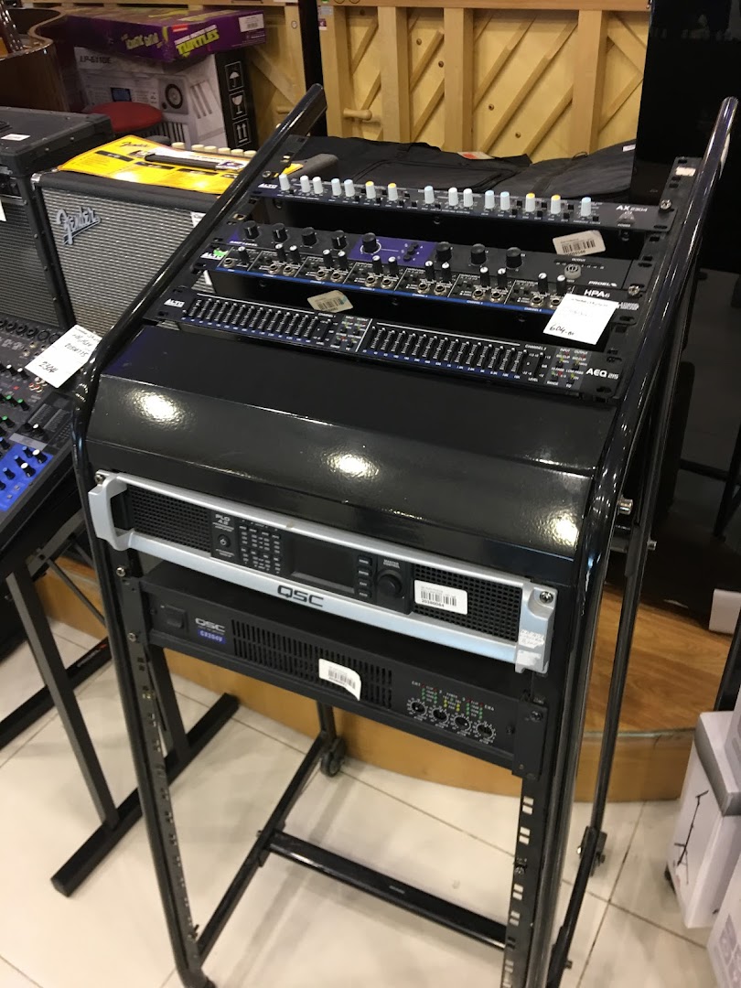 A rack of audio equipment including mixers and amplifiers is displayed in a store.