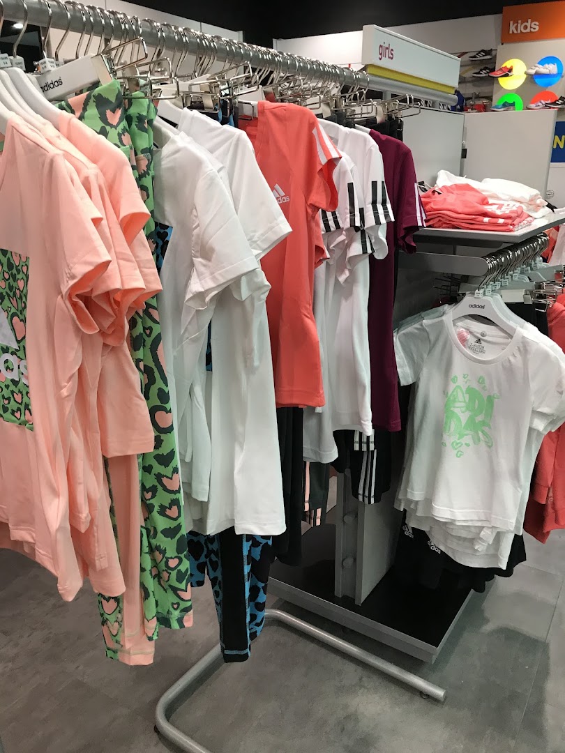 Adidas store interior displaying colorful t-shirts and leggings for girls.