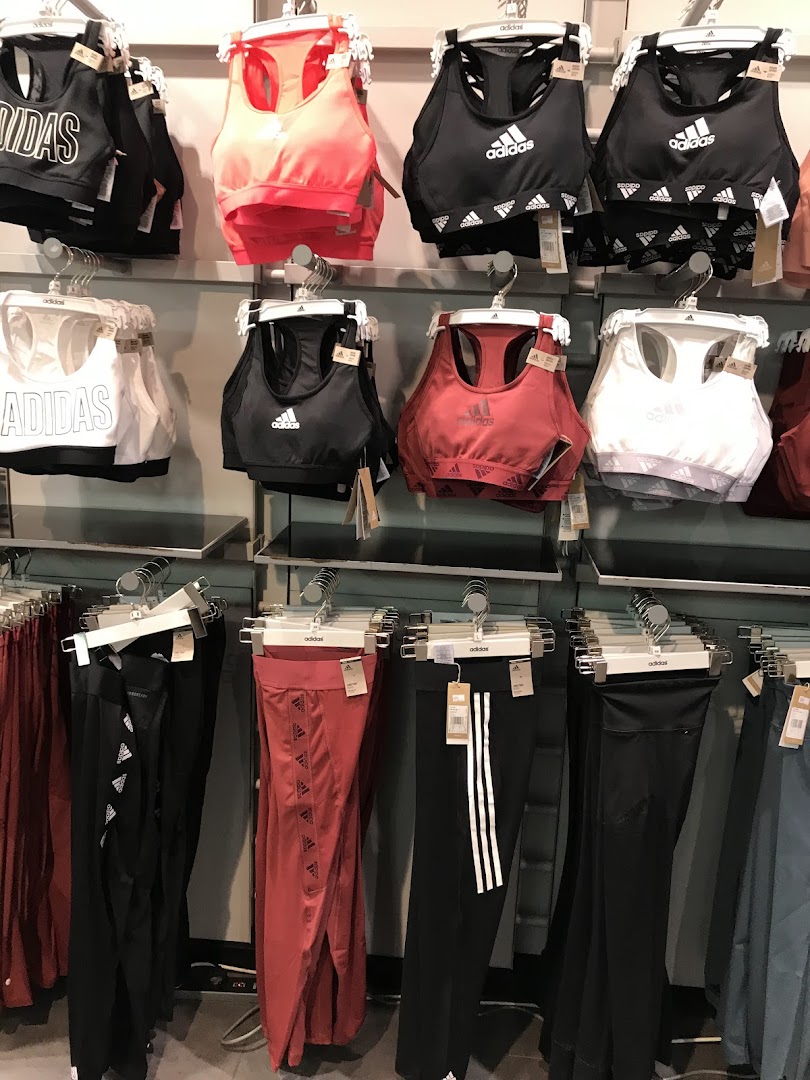 Adidas sports bras and leggings displayed on racks in a retail store.