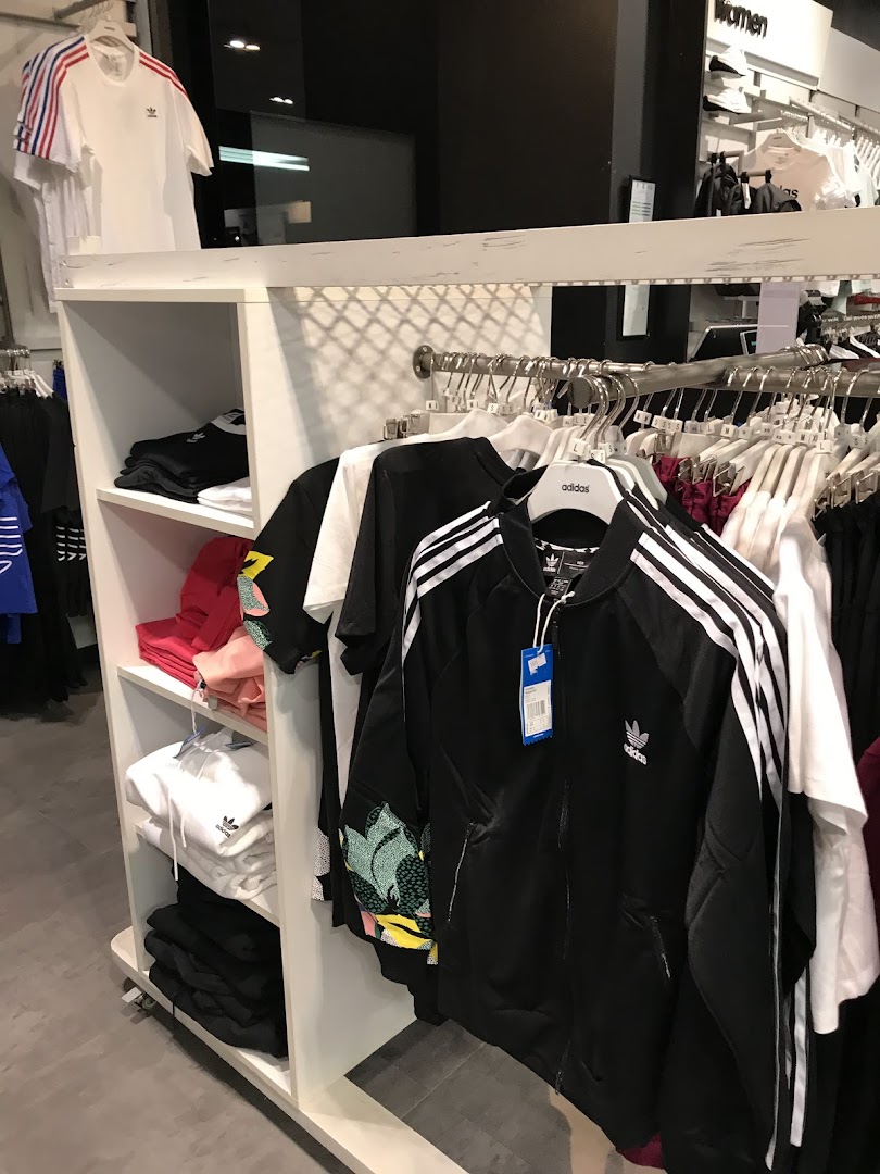 Interior view of an Adidas store showcasing various apparel like jackets, t-shirts, and hoodies.
