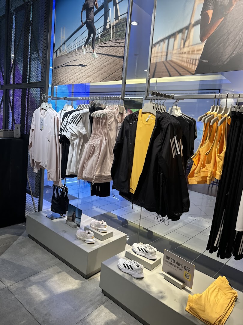 Interior of an Adidas store showcasing athletic apparel and footwear, with promotional signage.