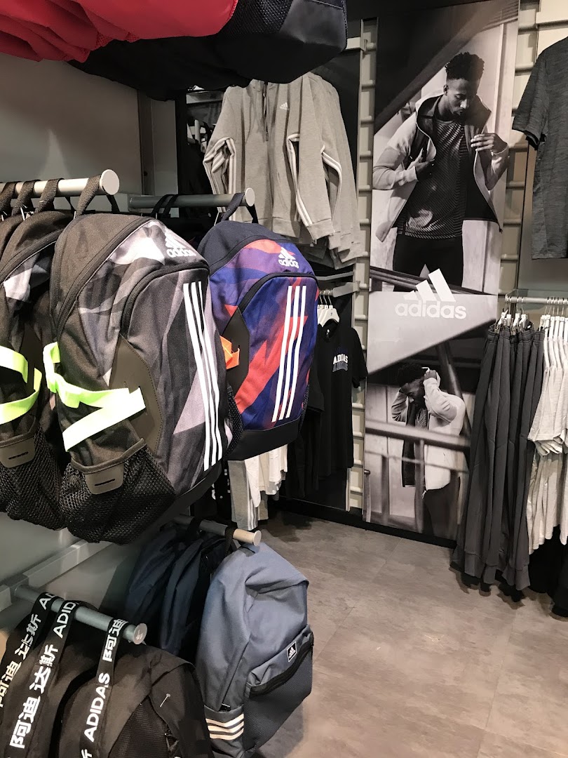 Adidas store interior showcasing backpacks, hoodies, and apparel with brand imagery.