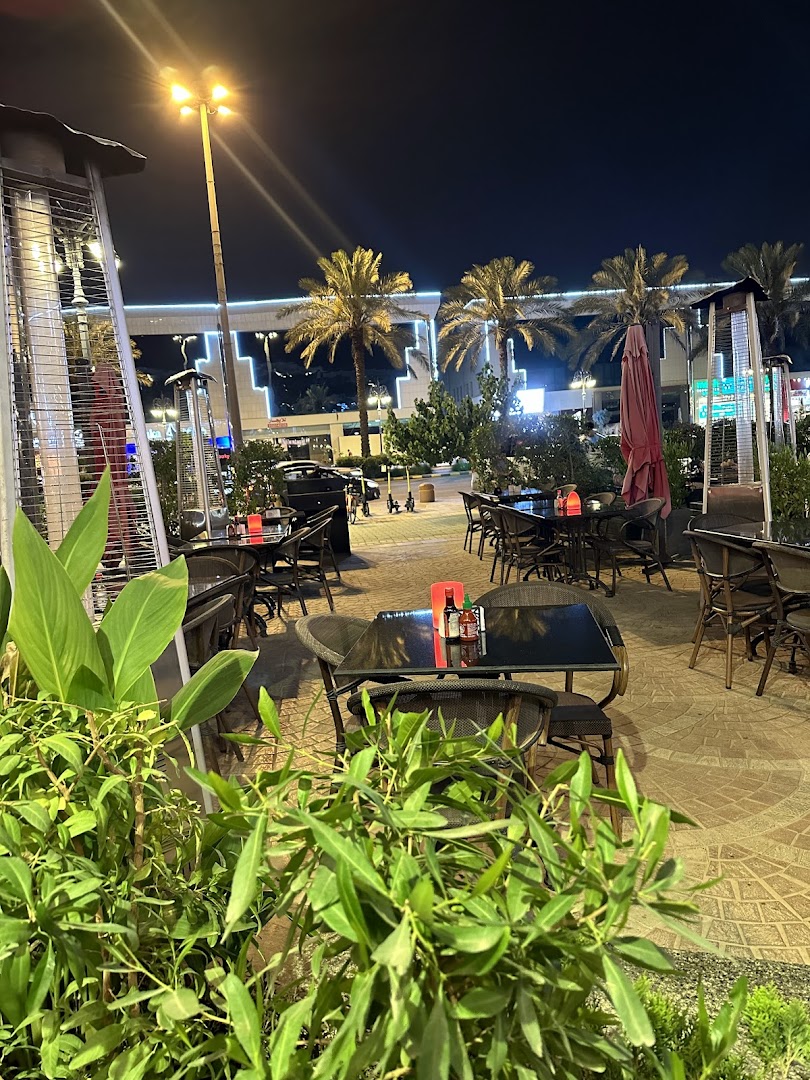 Outdoor seating area of Agus Restaurant at night with palm trees and heaters.