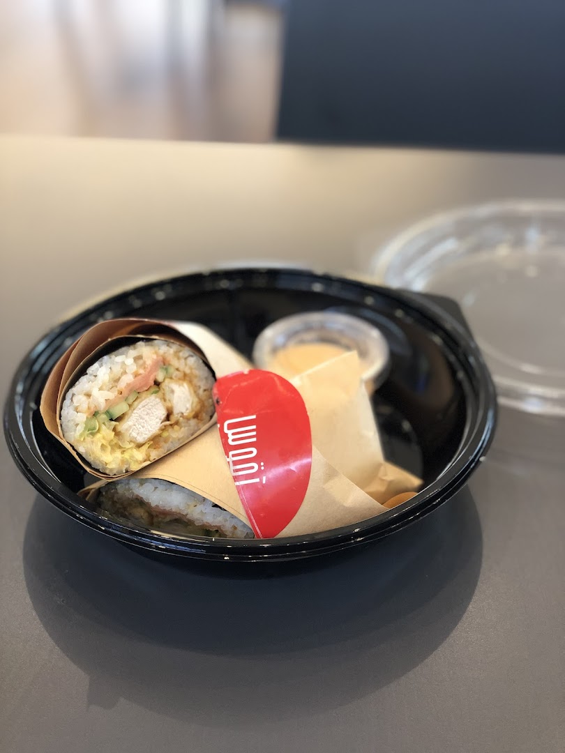 A close-up of a sushi roll and a chicken wrap in a black takeout container.