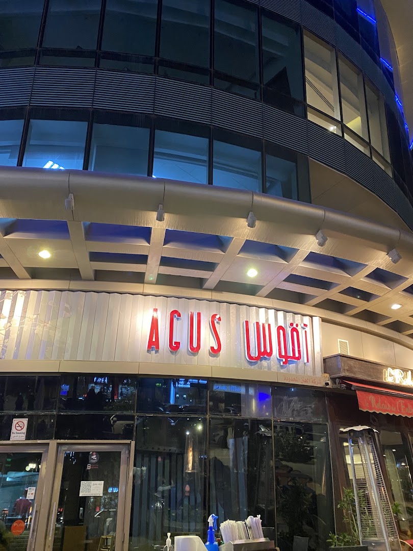 The illuminated storefront of Agus Restaurant at night, featuring a modern facade and large glass windows.