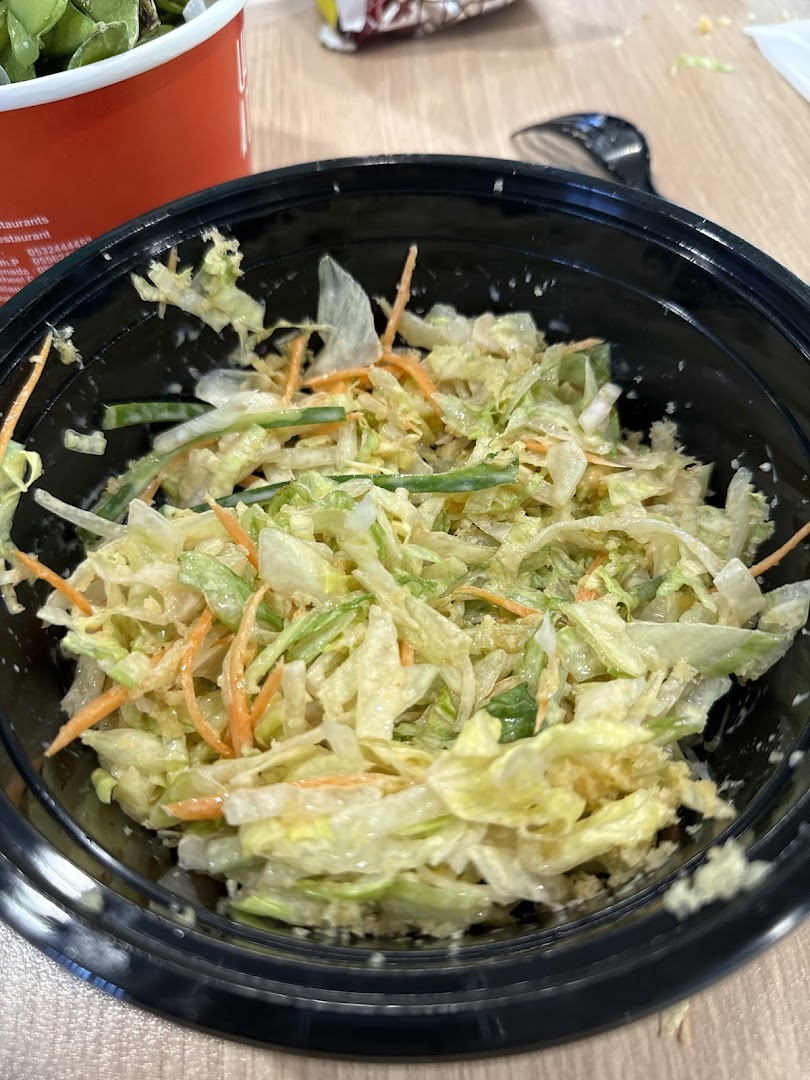 A close-up shot of a fresh coleslaw salad in a black bowl.