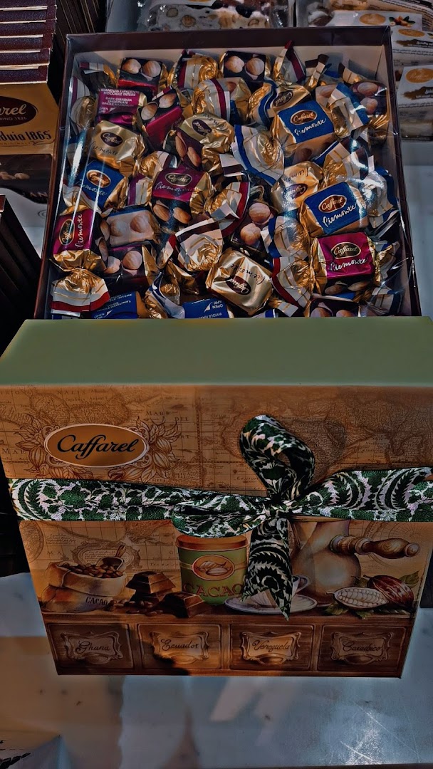 A gift box filled with individually wrapped chocolates, tied with a decorative ribbon.