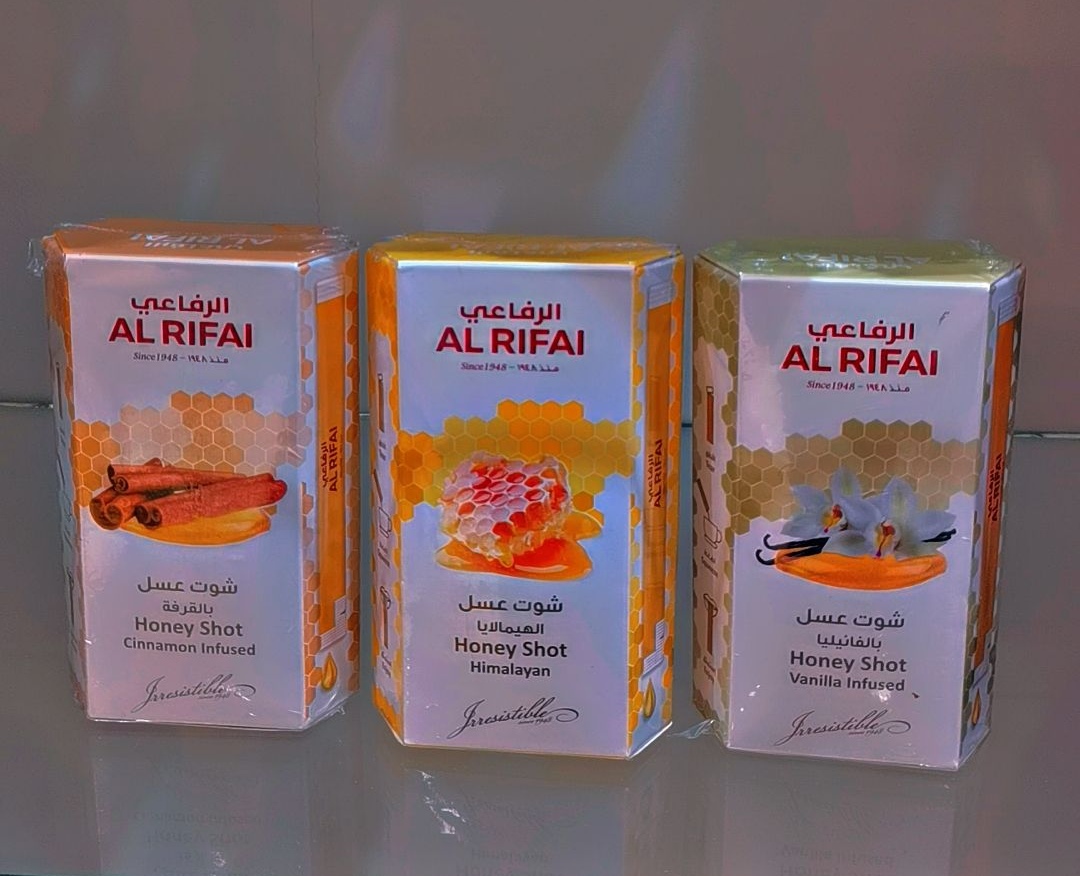 Three hexagonal boxes of Al Rifai Honey Shots with different infusions: Cinnamon, Himalayan, and Vanilla.