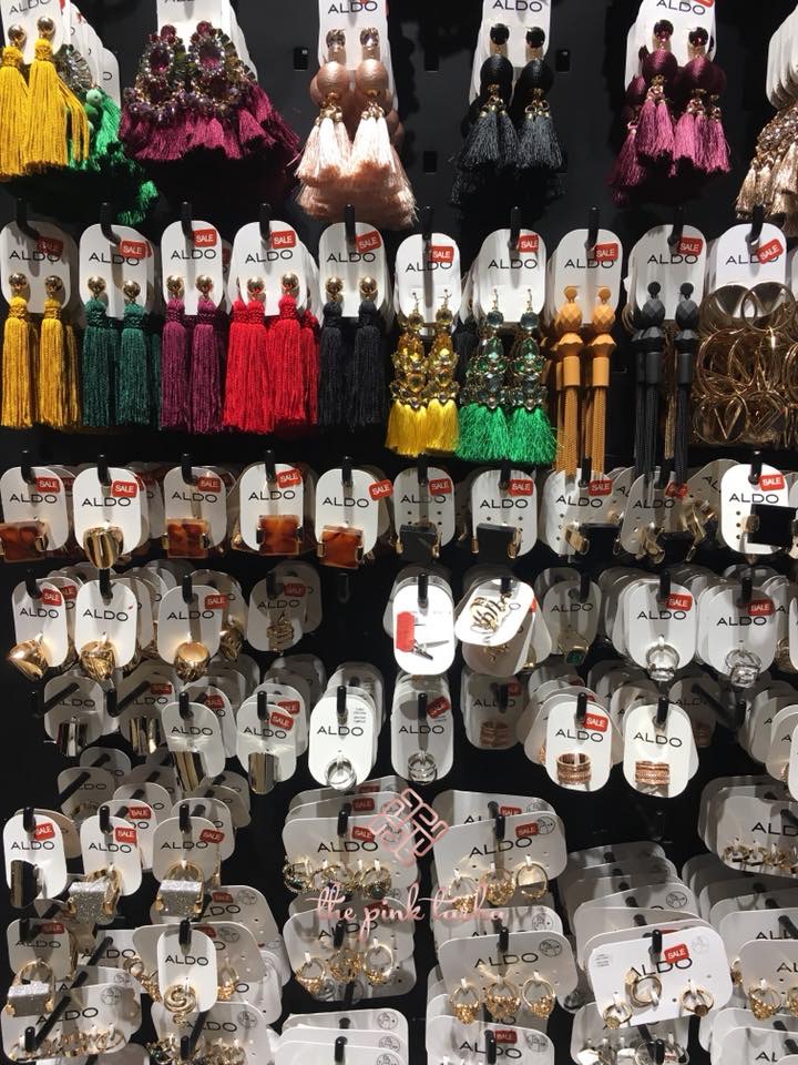 A wall display of various Aldo earrings and accessories, featuring tassels, hoops, and rings.