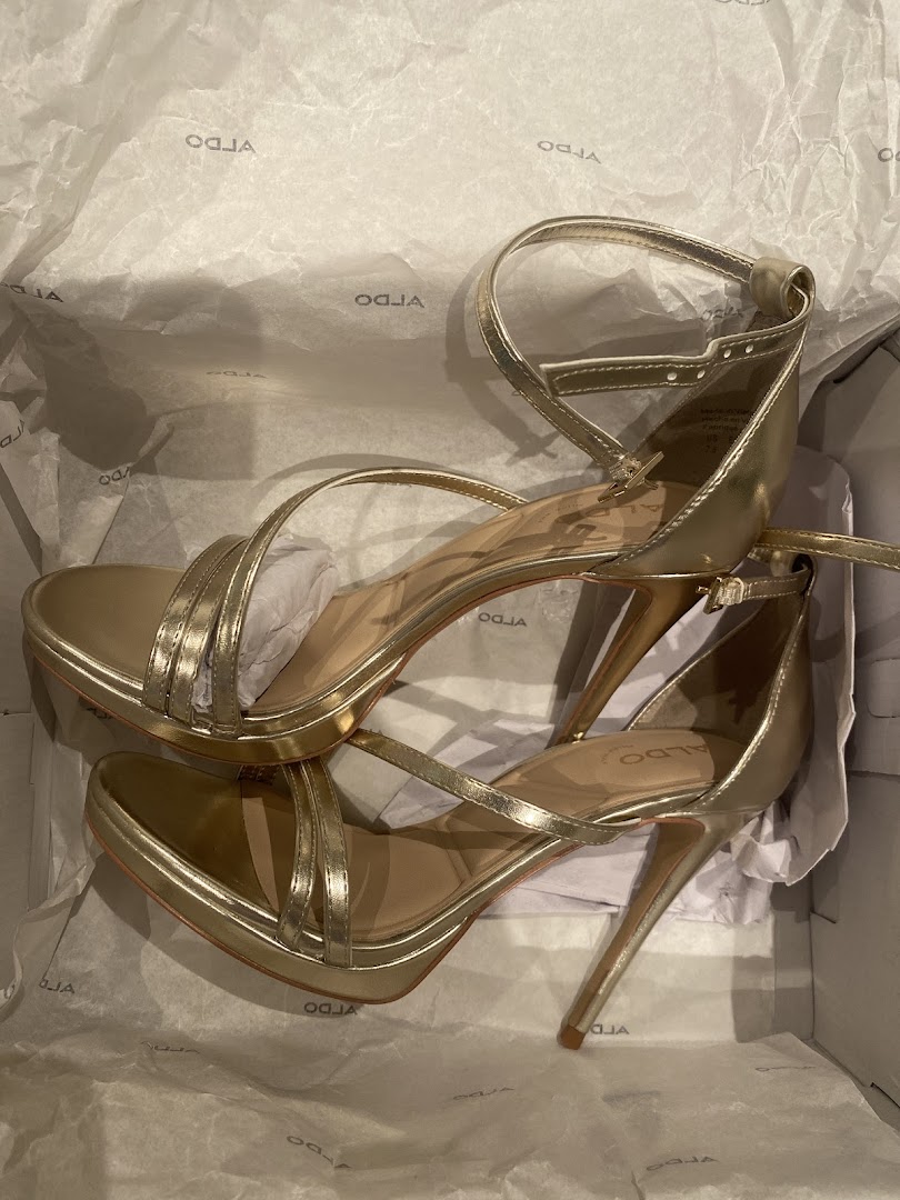 A pair of gold strappy high-heeled sandals in an Aldo shoe box.
