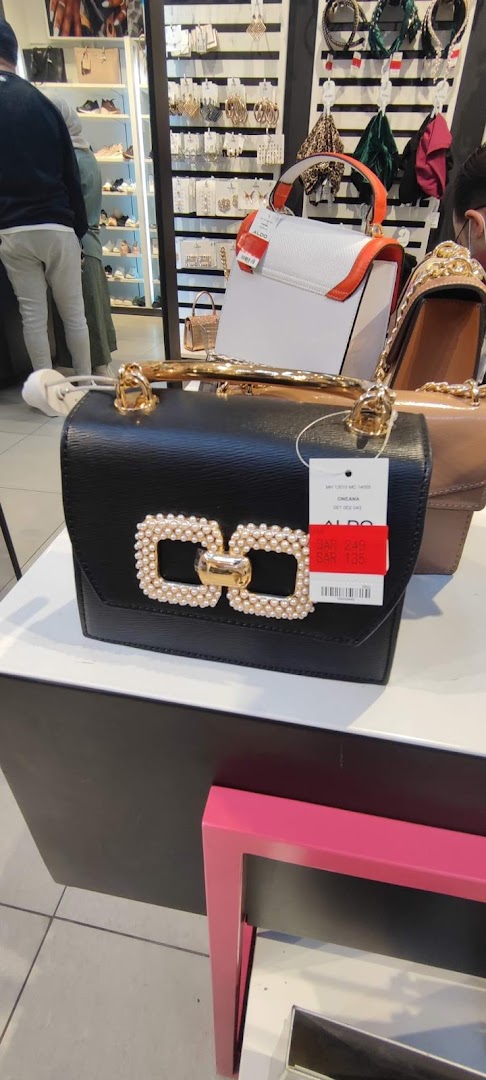 A black handbag with pearl embellishments and gold hardware is displayed.