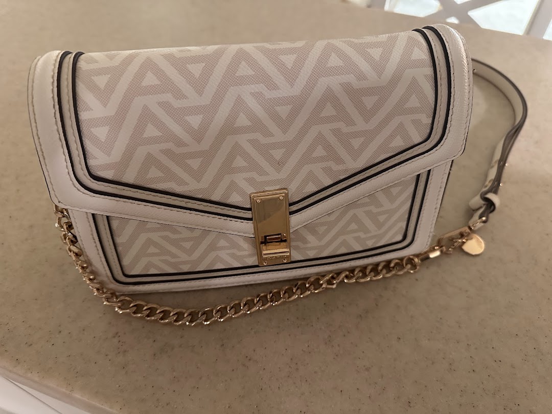 A white and beige patterned shoulder bag with a gold chain strap and clasp.