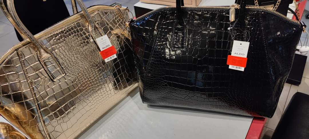 Two stylish Aldo handbags, one gold and one black, with crocodile texture and price tags.