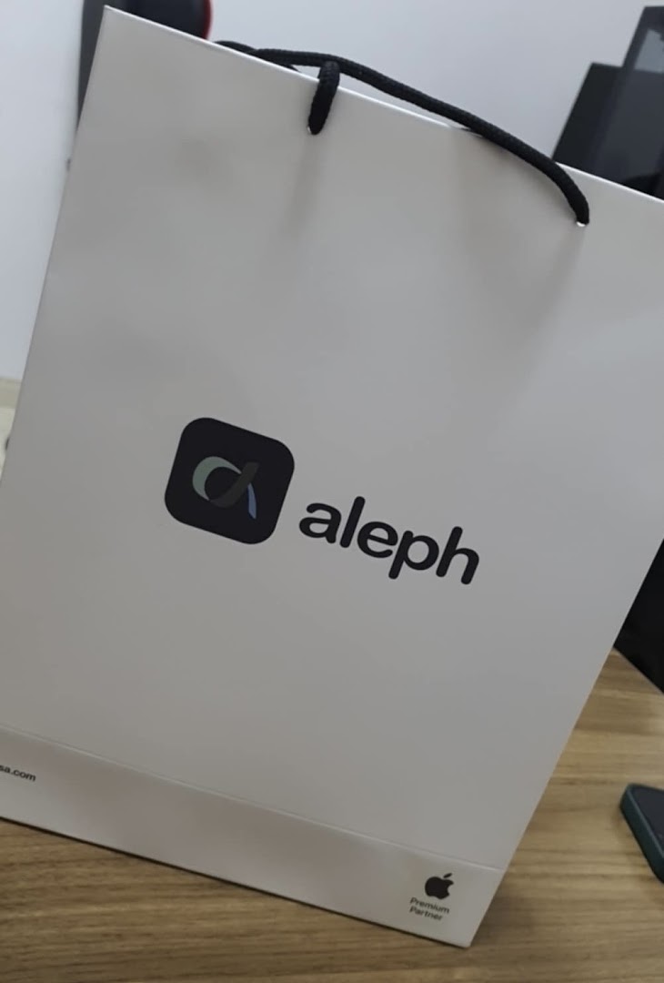 A white shopping bag with the Aleph logo and Apple Premium Partner branding.