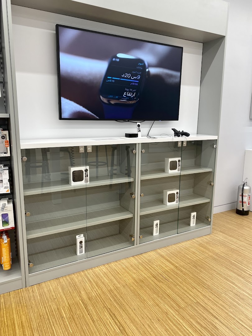 A display cabinet with Apple products and a large screen showing an Apple Watch interface.
