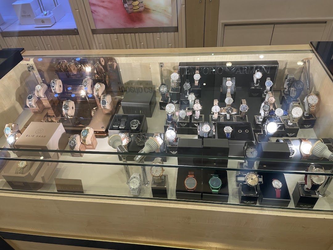 A display case filled with various luxury watches from brands like Emporio Armani and Elie Saab.