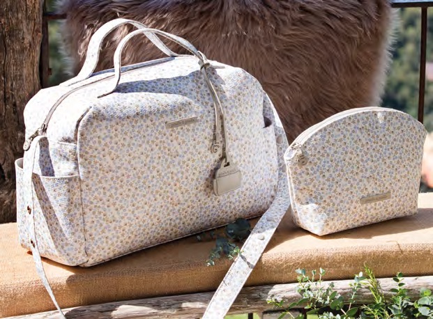 A floral print diaper bag and matching cosmetic bag are displayed on a rustic surface.