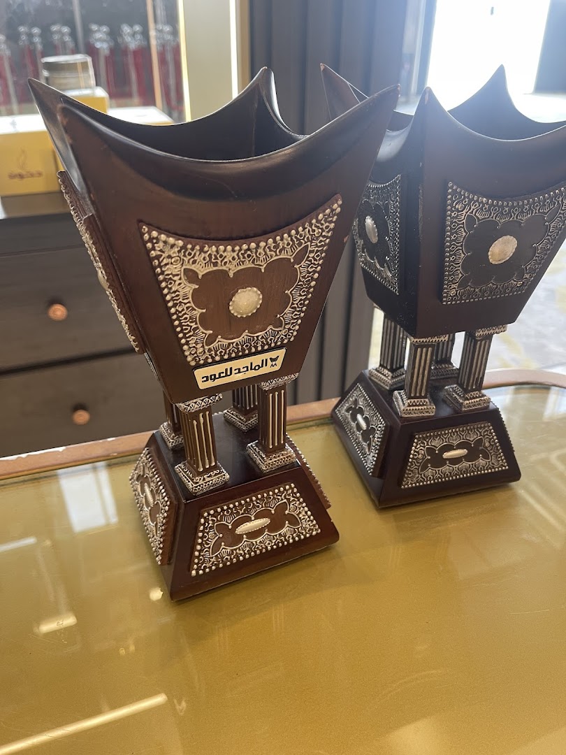 Two ornate wooden incense burners with silver detailing are displayed on a reflective surface.