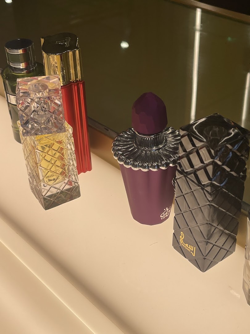 A collection of elegant perfume bottles displayed on a shelf, showcasing various designs and colors.