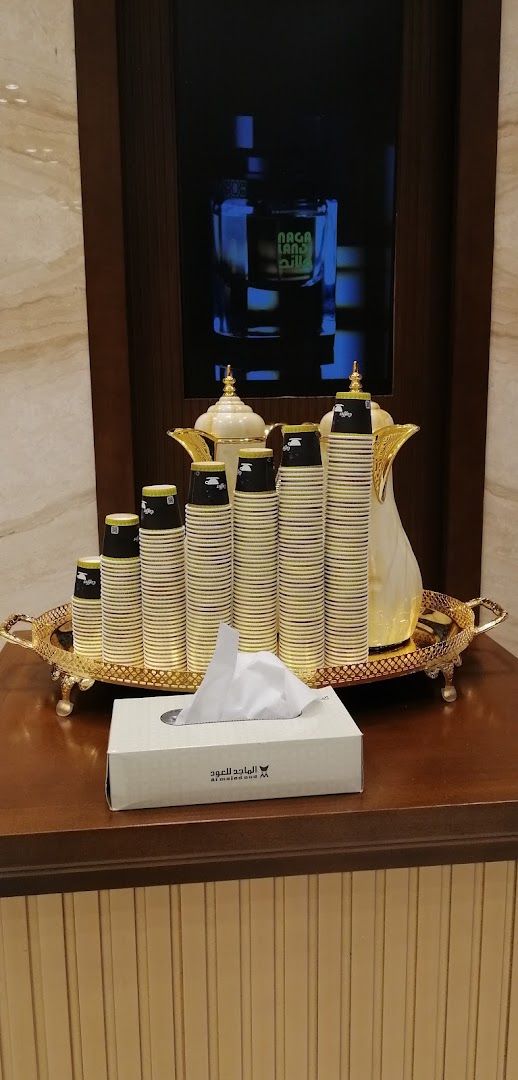 A tray with stacked paper cups, a thermos, and a tissue box, with a perfume bottle displayed in the background.