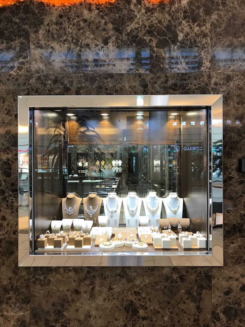 A well-lit jewelry store display window showcasing necklaces and rings on mannequins and stands.