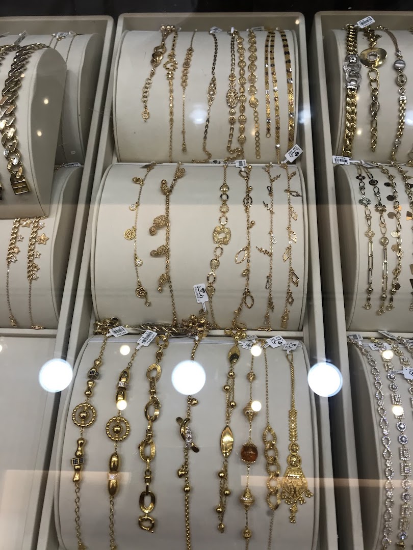 A display of various gold bracelets with intricate designs and charms.