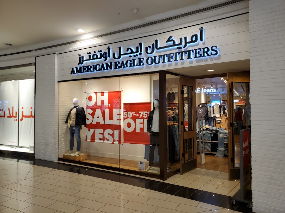 The storefront of American Eagle Outfitters, featuring mannequins and sale signage in the window.
