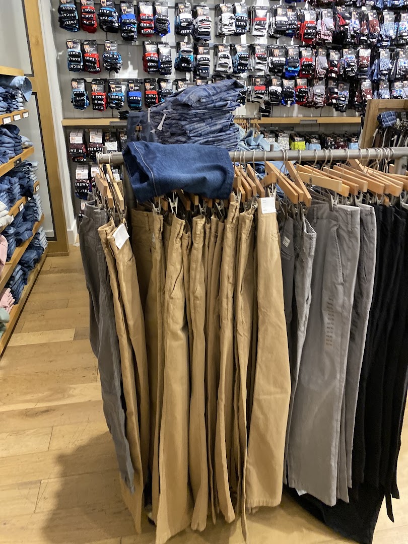Pants and socks displayed on racks and shelves inside an American Eagle store.