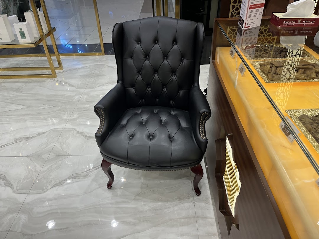 A black leather armchair sits next to a display case filled with aromatic wood chips at Arabian Oud.