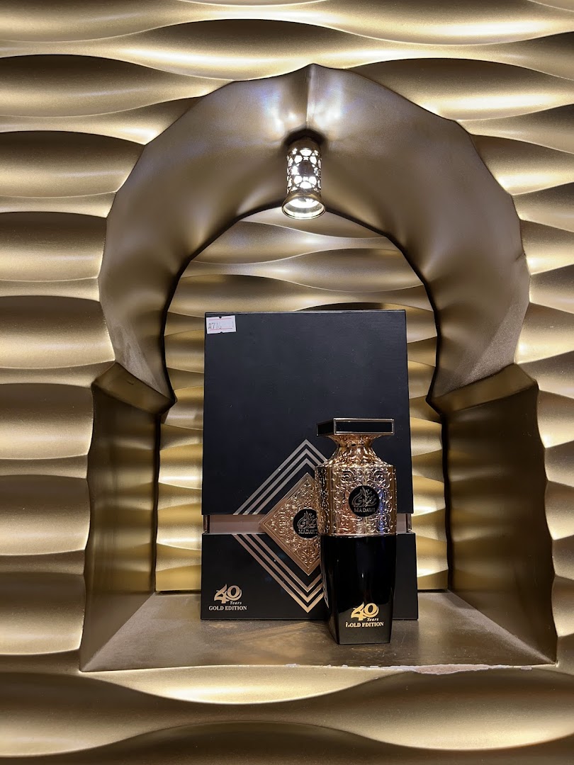A luxurious perfume bottle and its packaging displayed in an ornate golden alcove.