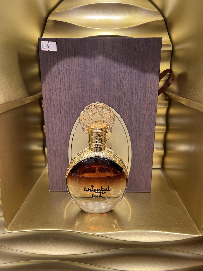 A bottle of 'Oriental Oud' perfume displayed with its packaging in a golden setting.