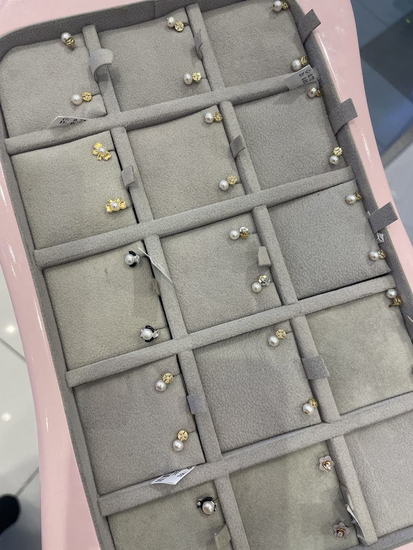 A display case filled with delicate gold and pearl earrings for children.
