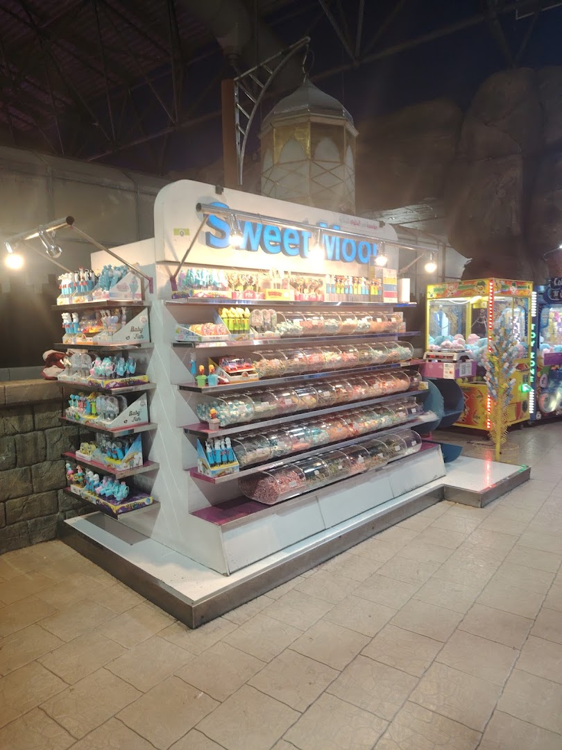 A brightly lit candy display with various sweets and toys in a shopping mall.