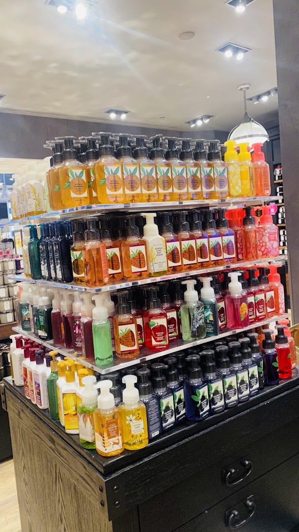 A display of various scented hand soaps in clear bottles with pumps.