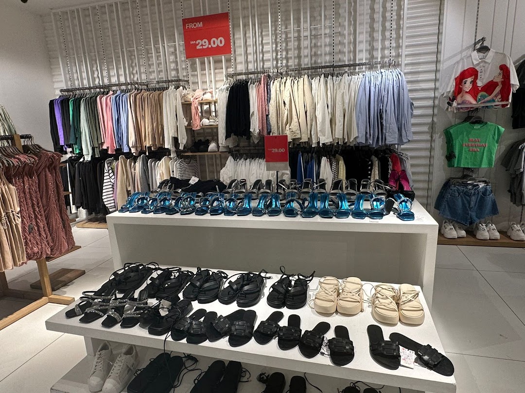 A retail store display featuring a wide selection of women's shoes and clothing, with a sale sign.