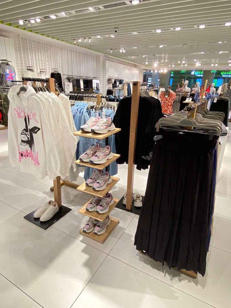 Interior view of a clothing store showcasing apparel and footwear on display racks.
