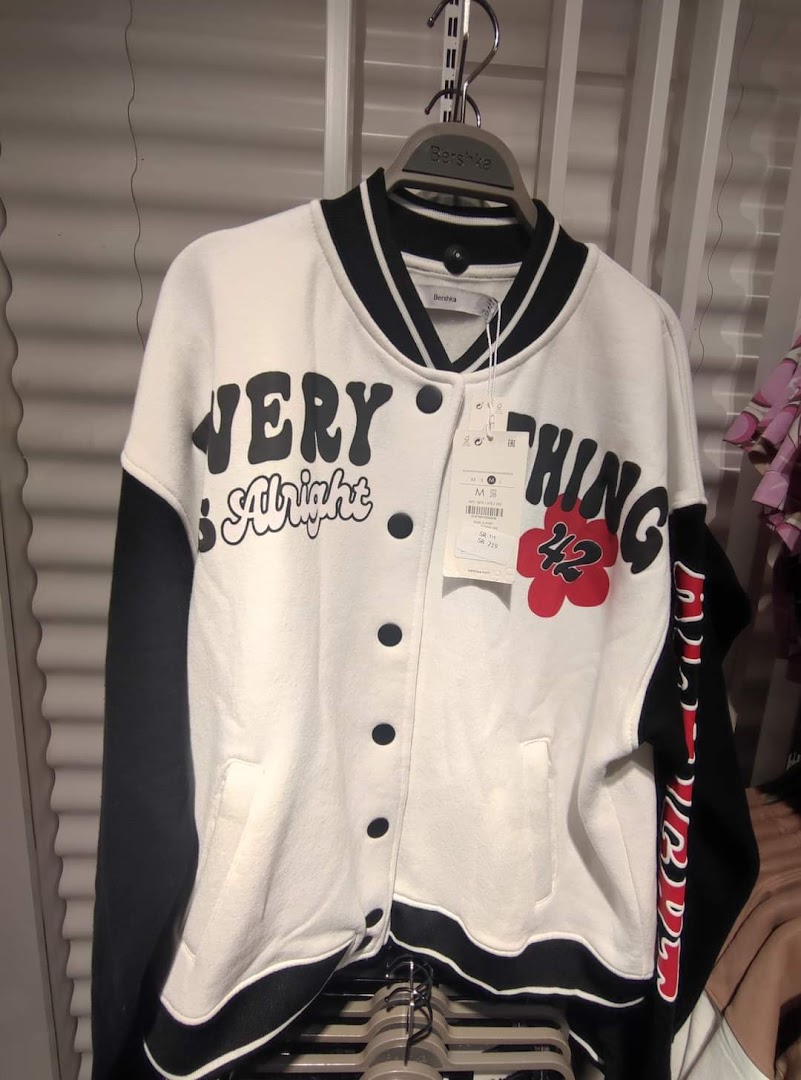 A white and black varsity jacket with bold text and a floral design.