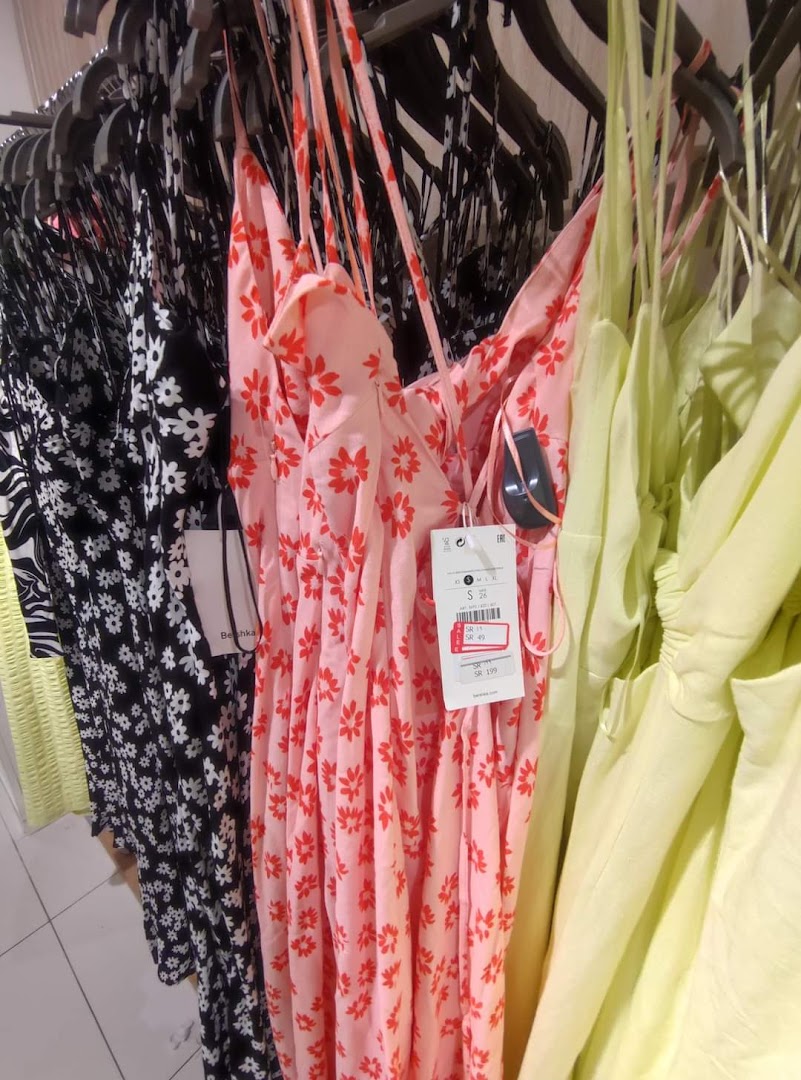A rack of colorful floral print dresses, including pink and black options.