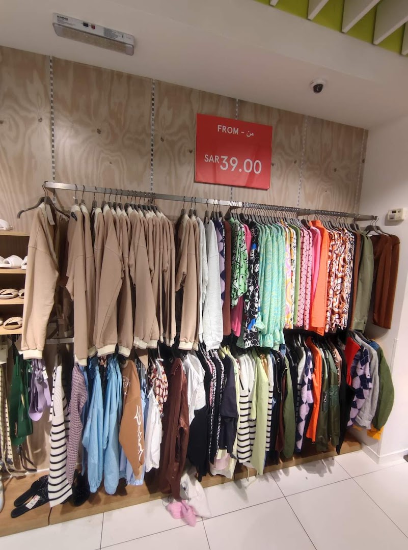 A clothing store display featuring a variety of colorful garments on hangers and a sale sign.