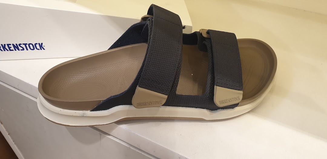 A close-up view of a stylish Birkenstock sandal with dark straps and a comfortable cork footbed.