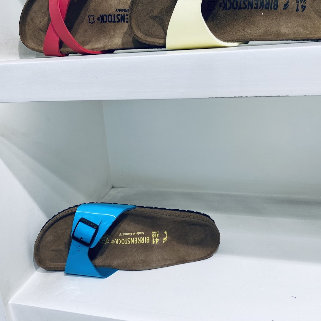 Close-up of Birkenstock sandals displayed on white shelves, showcasing vibrant colors.