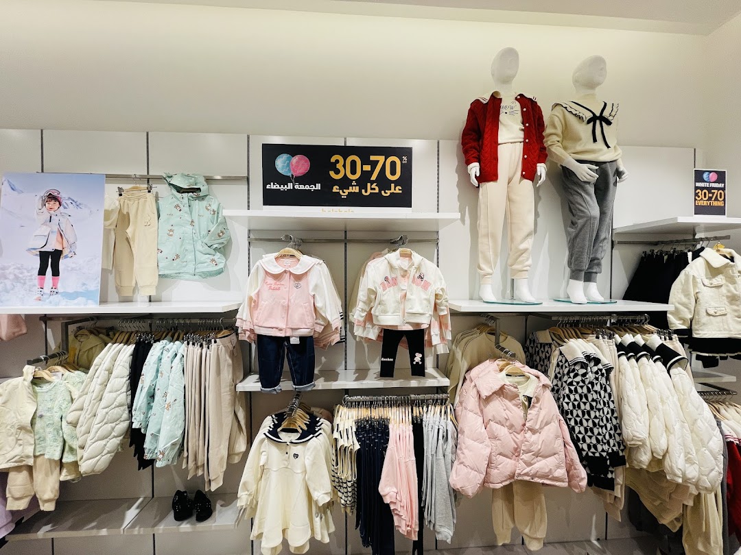 A retail shop display featuring children's winter clothing, including jackets, pants, and outfits on mannequins and racks.